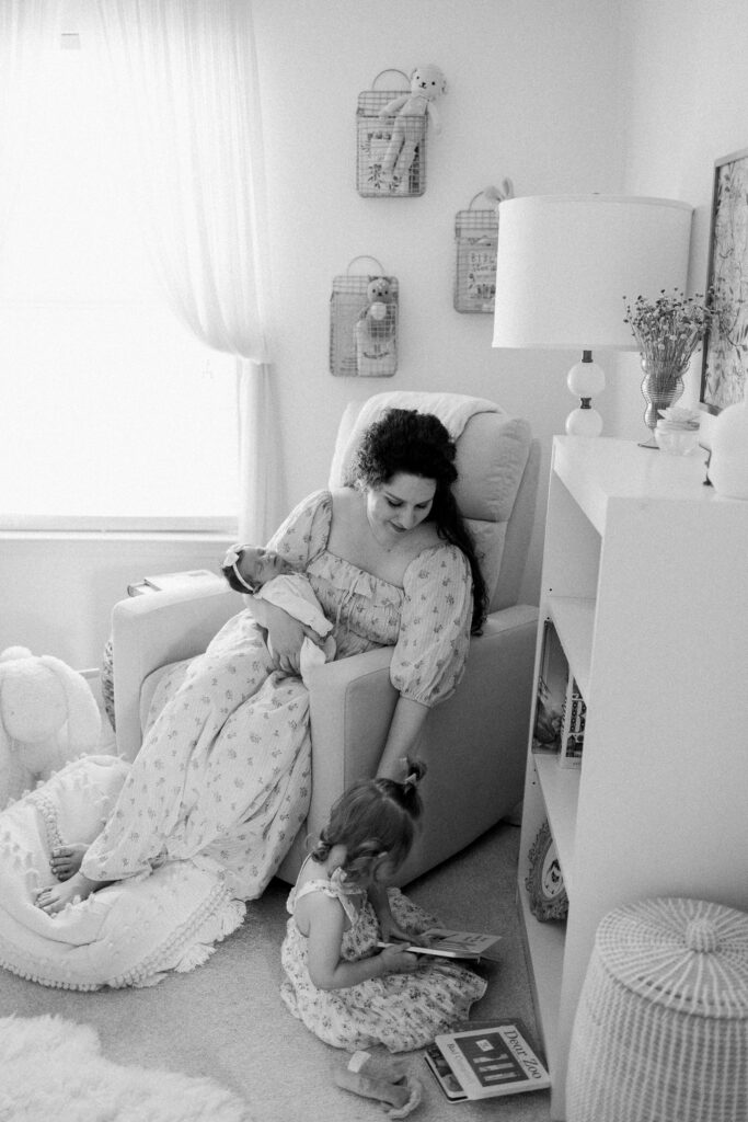 Mother with newborn baby and daughter in decorated nursery during in-home lifestyle session
