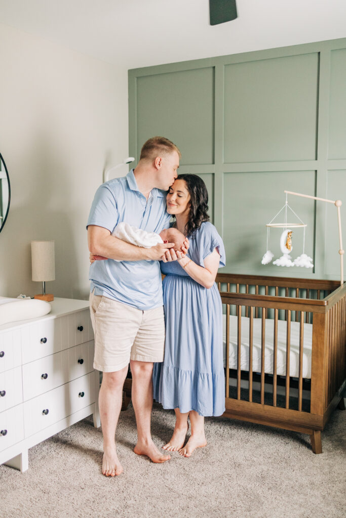 Parents with newborn baby in decorated nursery during in-home lifestyle session in Columbia South Carolina