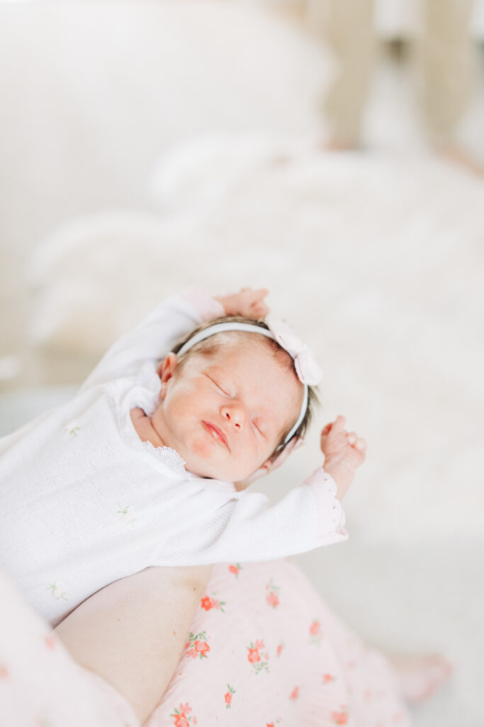 Close up of newborn stretching in mother's arms by Carters Creative located in South Carolina