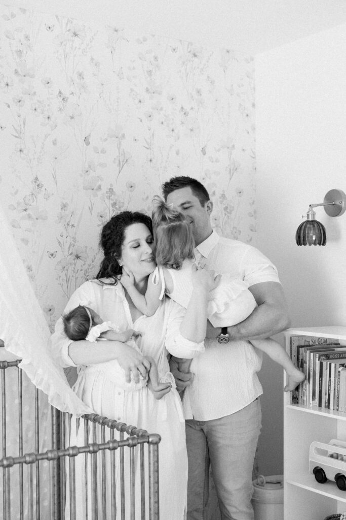 Parents with newborn baby in decorated nursery during in-home lifestyle session