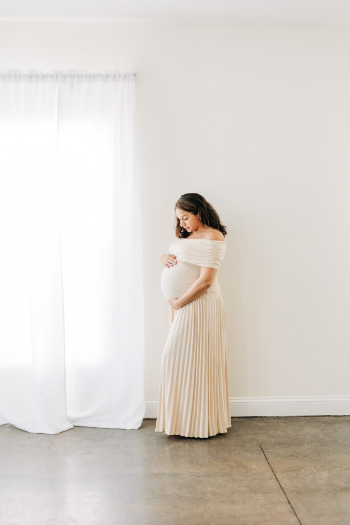 Pregnant mother posing and looking down at her baby by Carters Creative