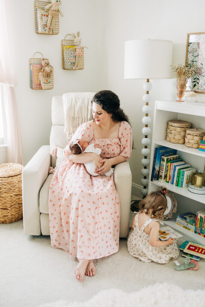 Mother holding newborn in decorated nursery in in-home lifestyle session