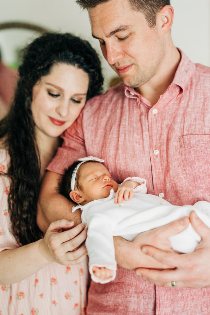 Parents posing with newborn during an in-home lifestyle session by Carters Creative