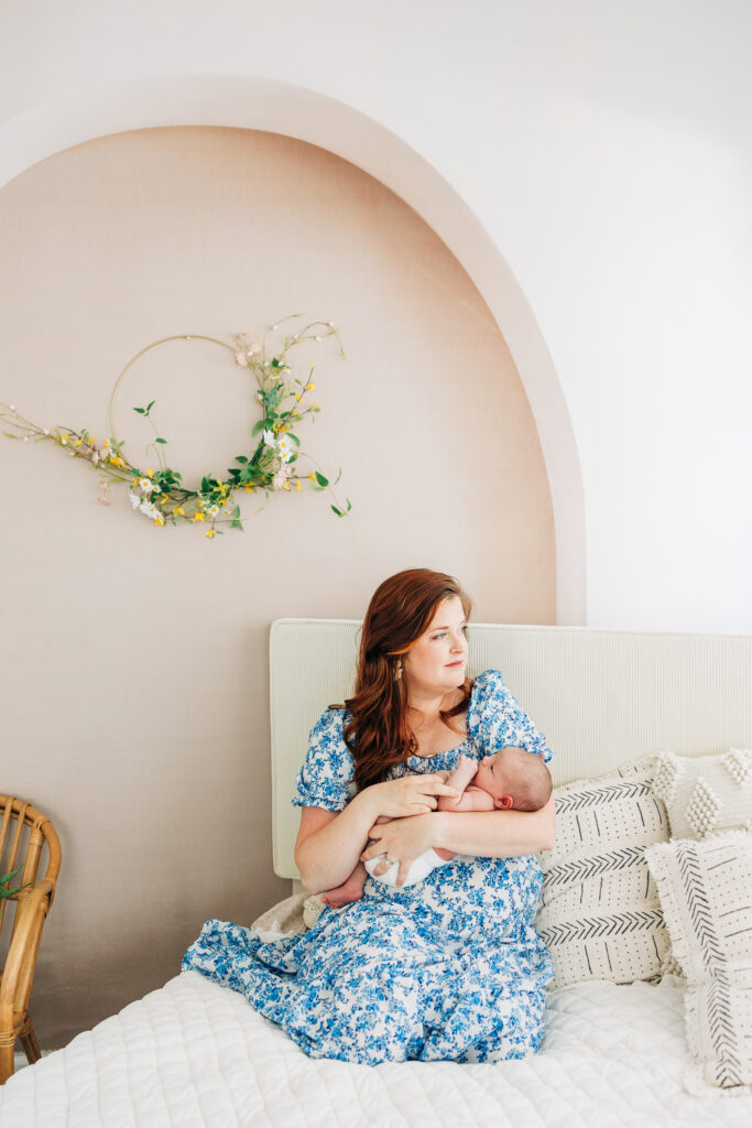 Mother with newborn baby in master bedroom during in-home lifestyle session