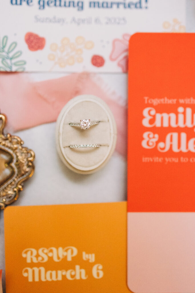 Close up of wedding rings on bright colored wedding invitation suite