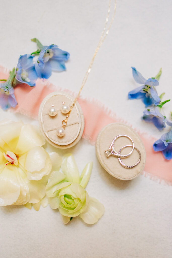 Flat lay wedding photography with bridal florals, ring box, and soft ribbon