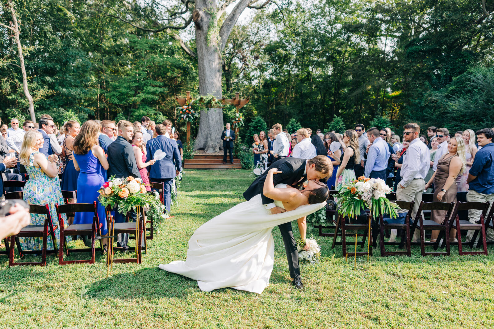 A candid photo of a bride and groom's first kiss as a married couple, with their guests celebrating