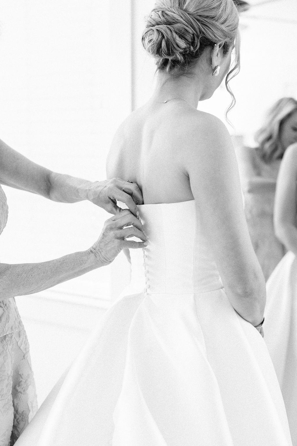A mother's hands are lacing up the back of her daughter's strapless wedding dress that was part of the pre wedding checklist