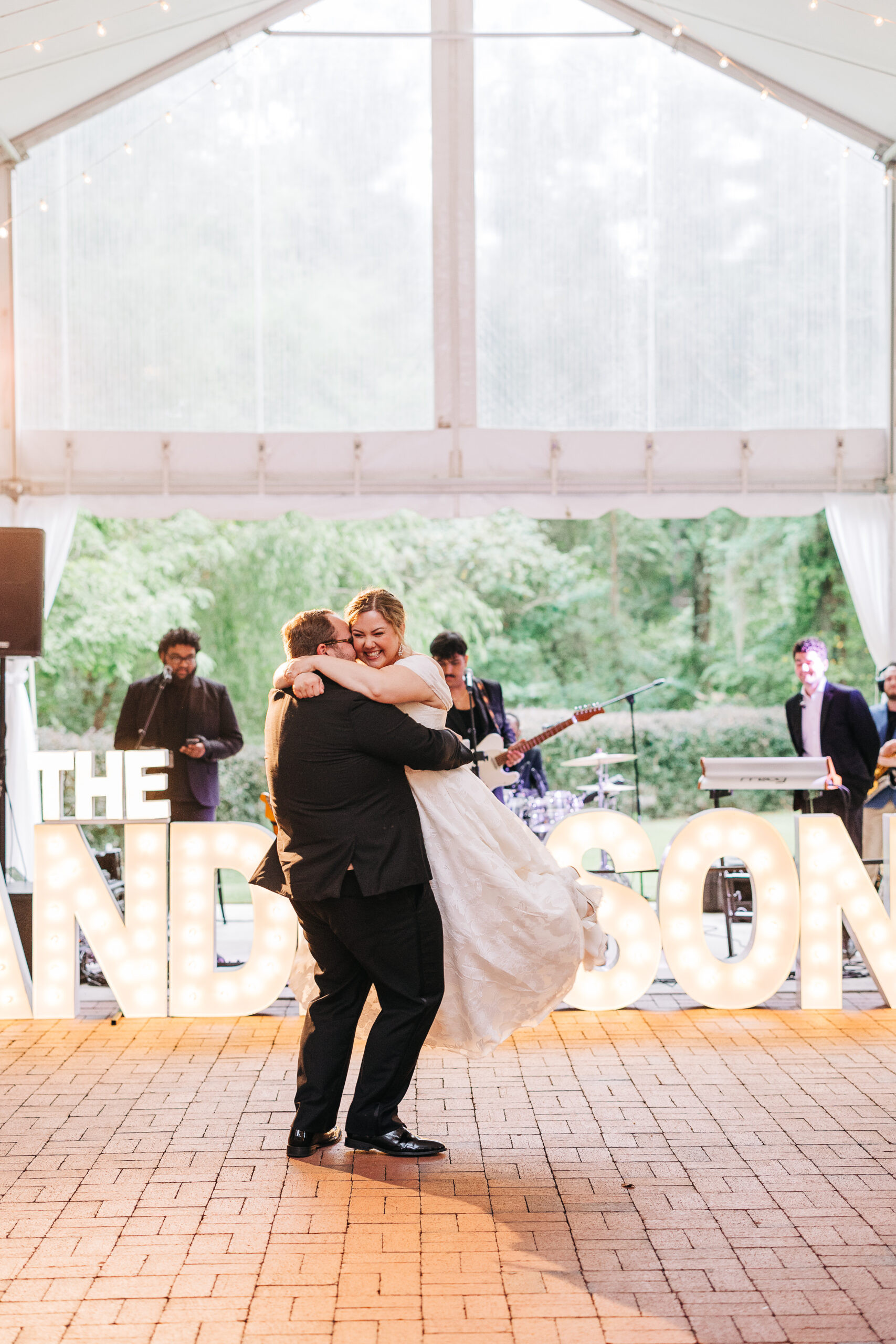 Groom lifts bride during first dance at outdoor wedding reception with live band these newly weds knew the question to ask your photographer