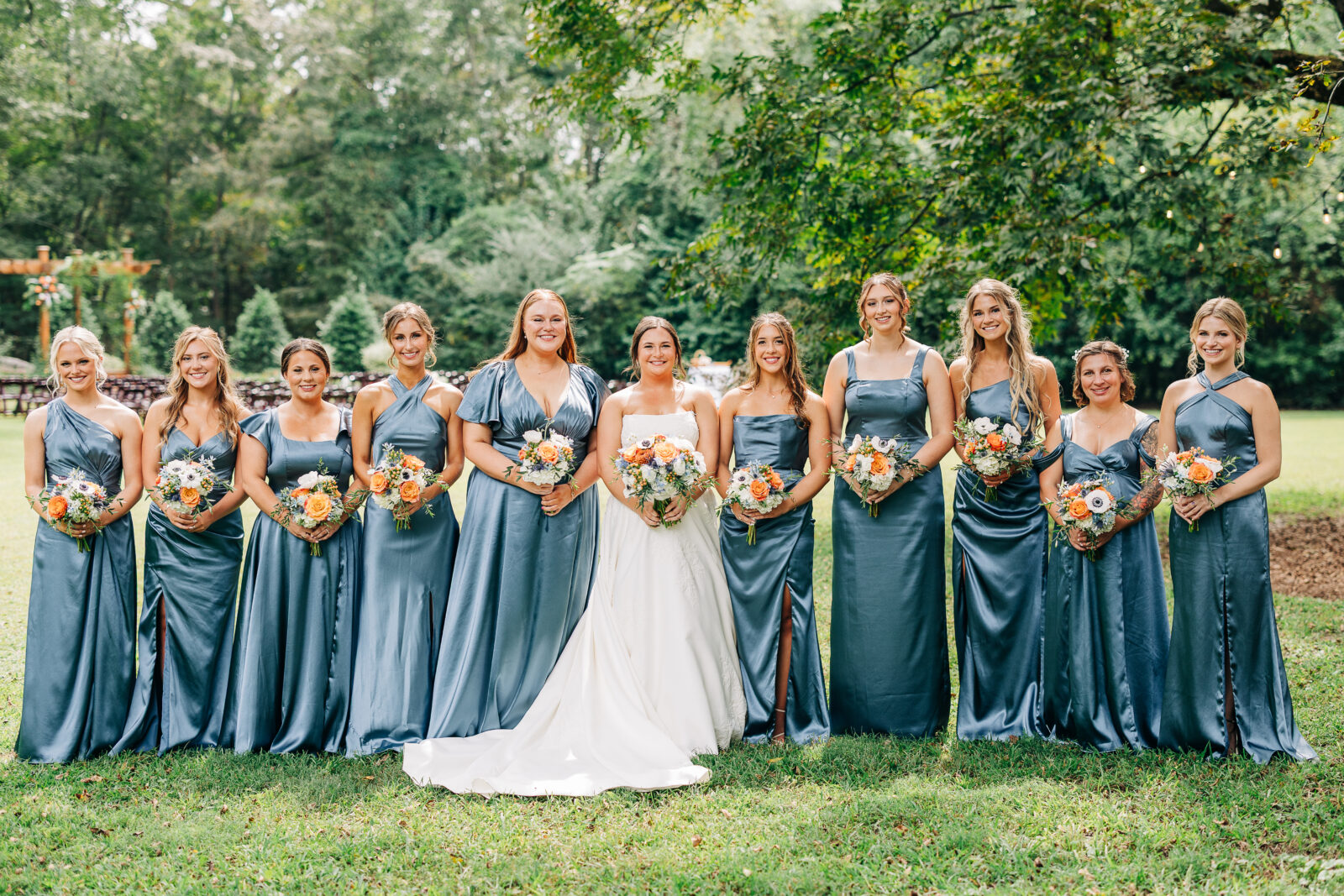 A full-length portrait of a wedding party standing together outdoors on the grass-A full-length portrait of a wedding party standing together