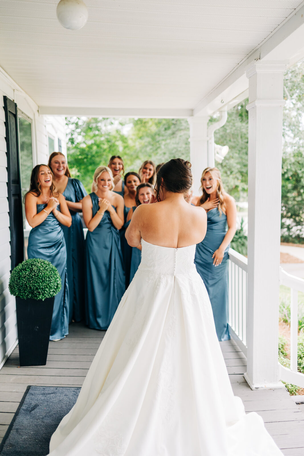 candid photo from behind a bride as she reveals her wedding dress to her excited bridesmaids