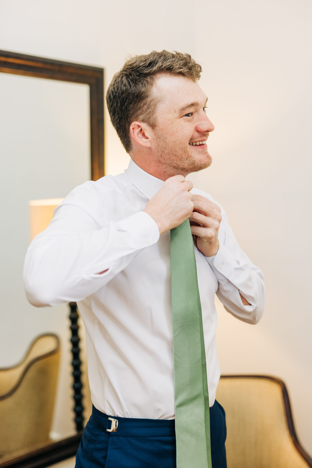 Groom adjusting his sage green tie while getting ready for the wedding ceremony in Columbia, SC