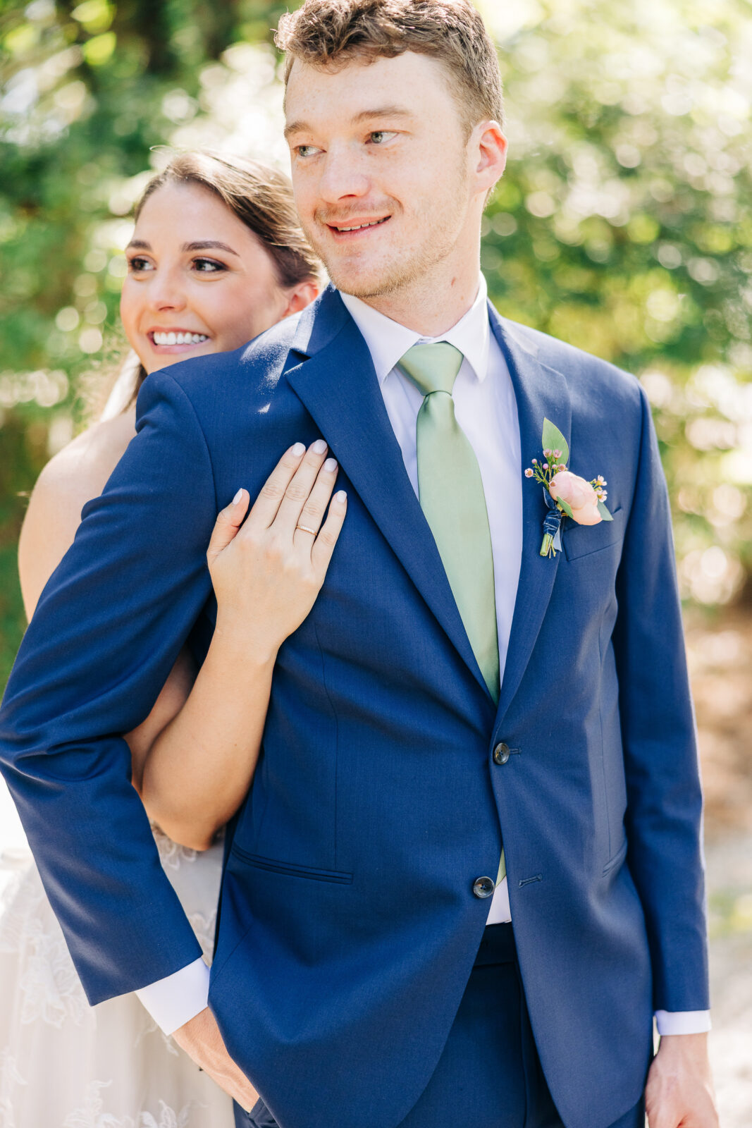 Bride and groom embracing during sunlit portraits outside at The Millstone at Adams Pond