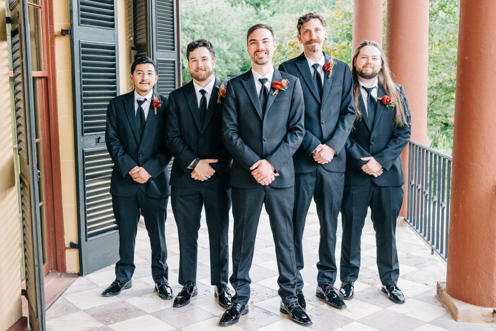 Groom and groomsmen portrait in black suits on the historic columned porch at Hampton-Preston Mansion