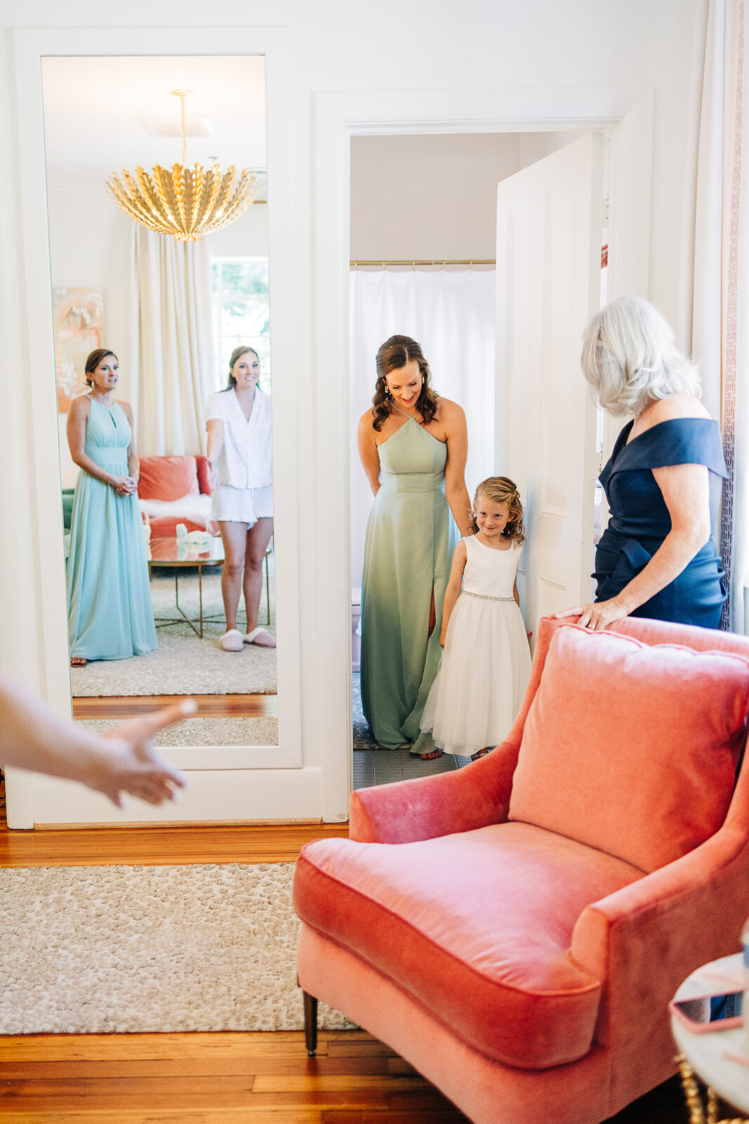 Bridal party getting ready with bridesmaids and flower girl in a brightly lit room with pink velvet chair in Columbia, SC