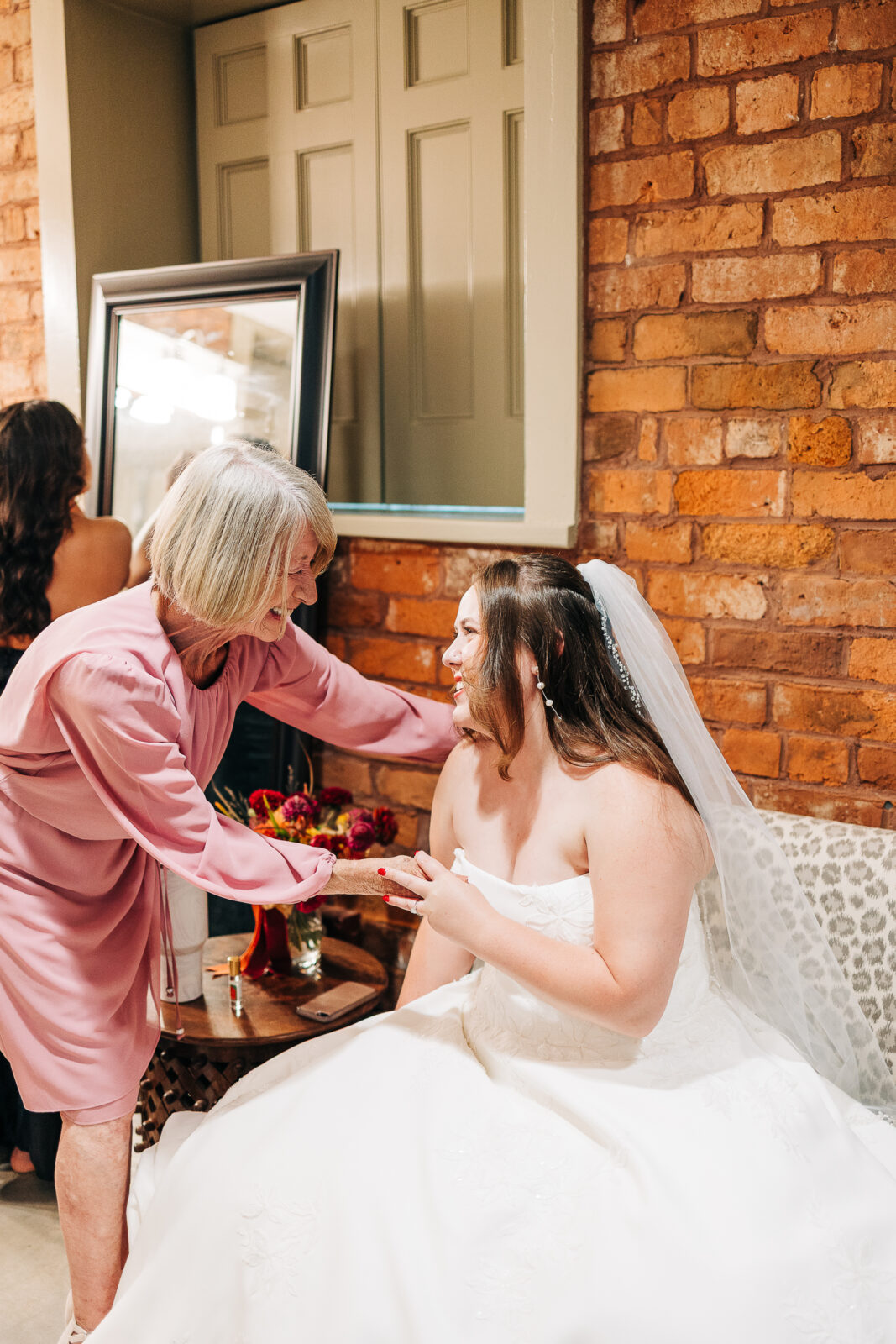 Emotional candid moment between bride and mother in the getting ready room with a brick wall, Columbia, SC