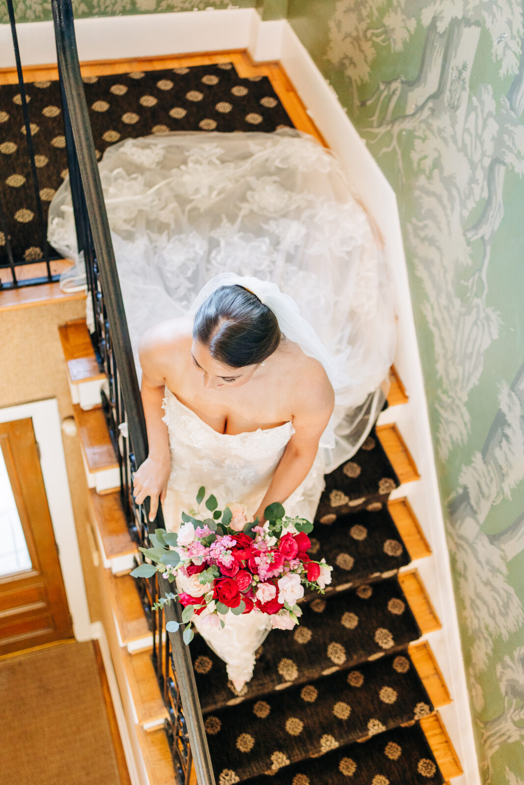 Overhead shot of bride walking down stairs in a flowing lace wedding dress at The Millstone at Adams Pond