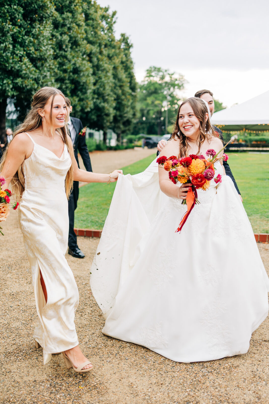 Smiling bride and groom wedding portrait holding vibrant red and orange bouquet at Hampton-Preston Mansion Gardens