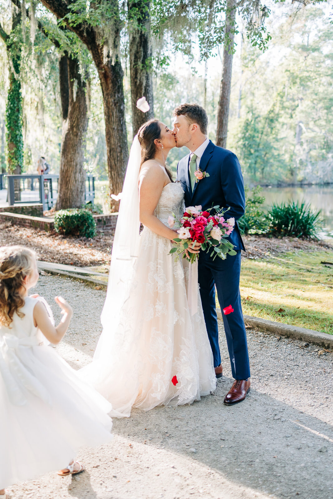 oyful bride and groom embracing during sunlit portraits with a vibrant red and pink bouquet in Columbia, SC