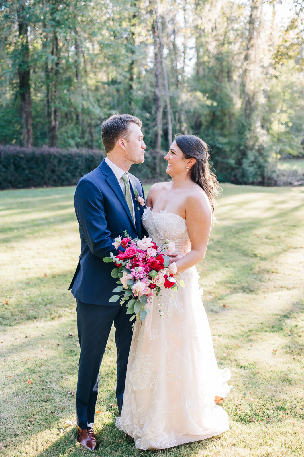 Romantic portrait of the bride and groom looking at each other in a sunny garden at The Millstone at Adams Pond