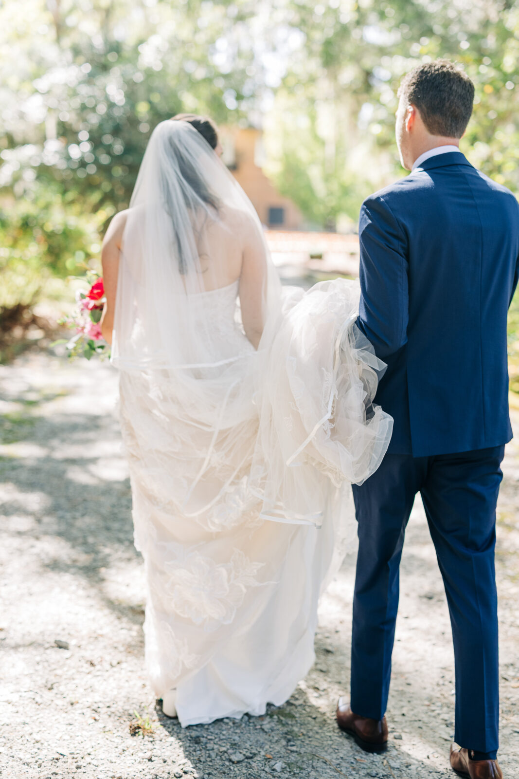 Bride and groom walking away together on a sunny gravel path after their wedding ceremony in Columbia, SC
