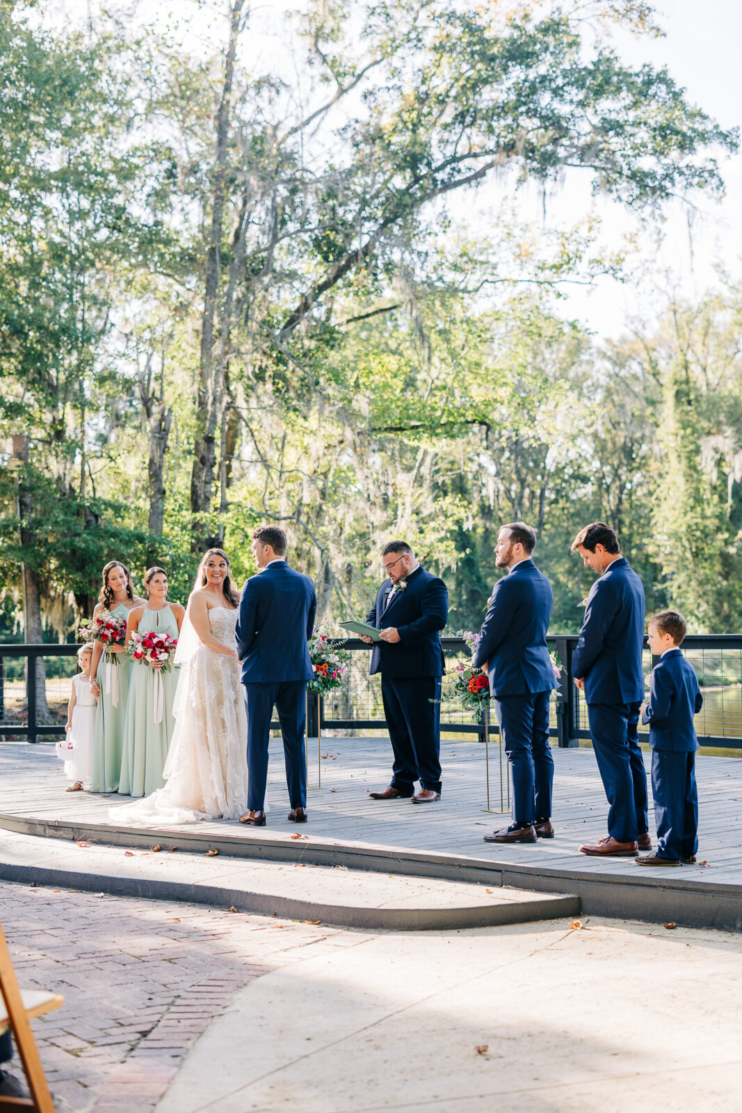 Bride smiling at groom during outdoor portraits surrounded by greenery at The Millstone at Adams Pond