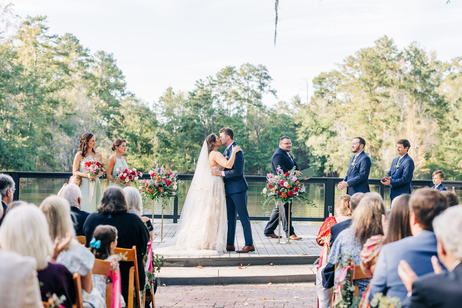 Wedding ceremony first kiss photo on the scenic deck overlooking the pond at The Millstone at Adams Pond