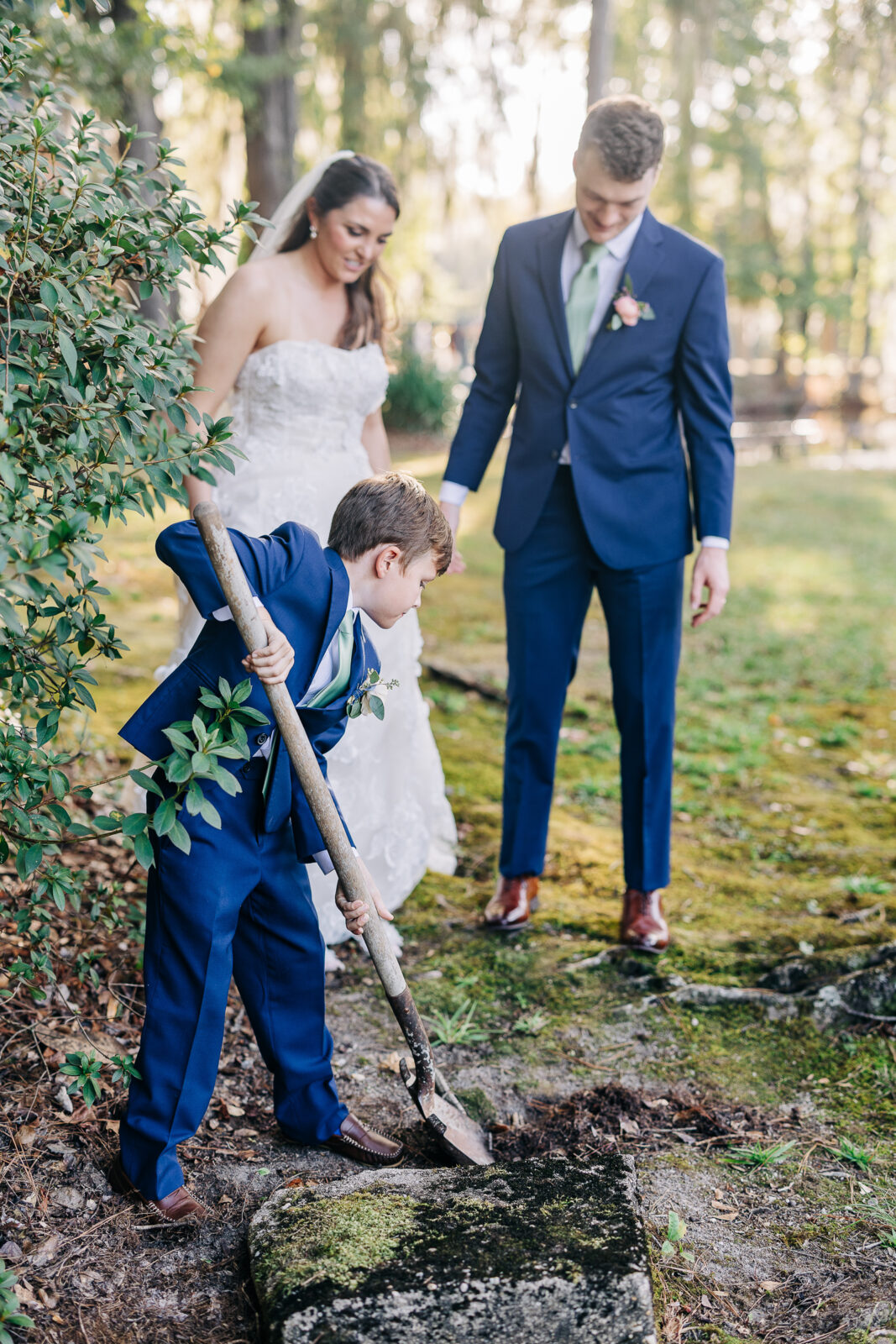 Young ring bearer or child digging during the wedding ceremony's tree planting ritual at Millstone at Adams Pond