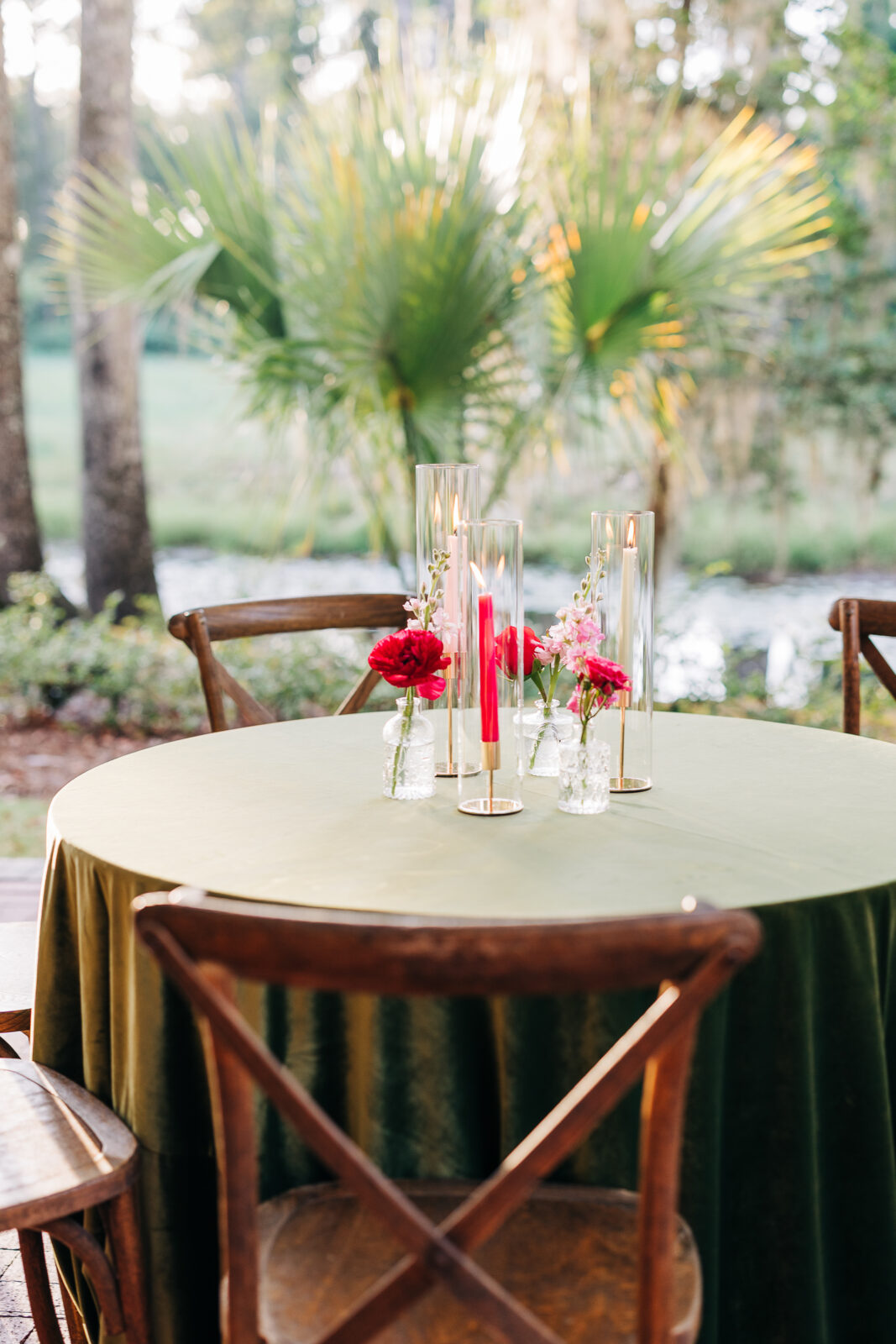 Wedding reception table setting with candles and flowers under palm trees at The Millstone at Adams Pond