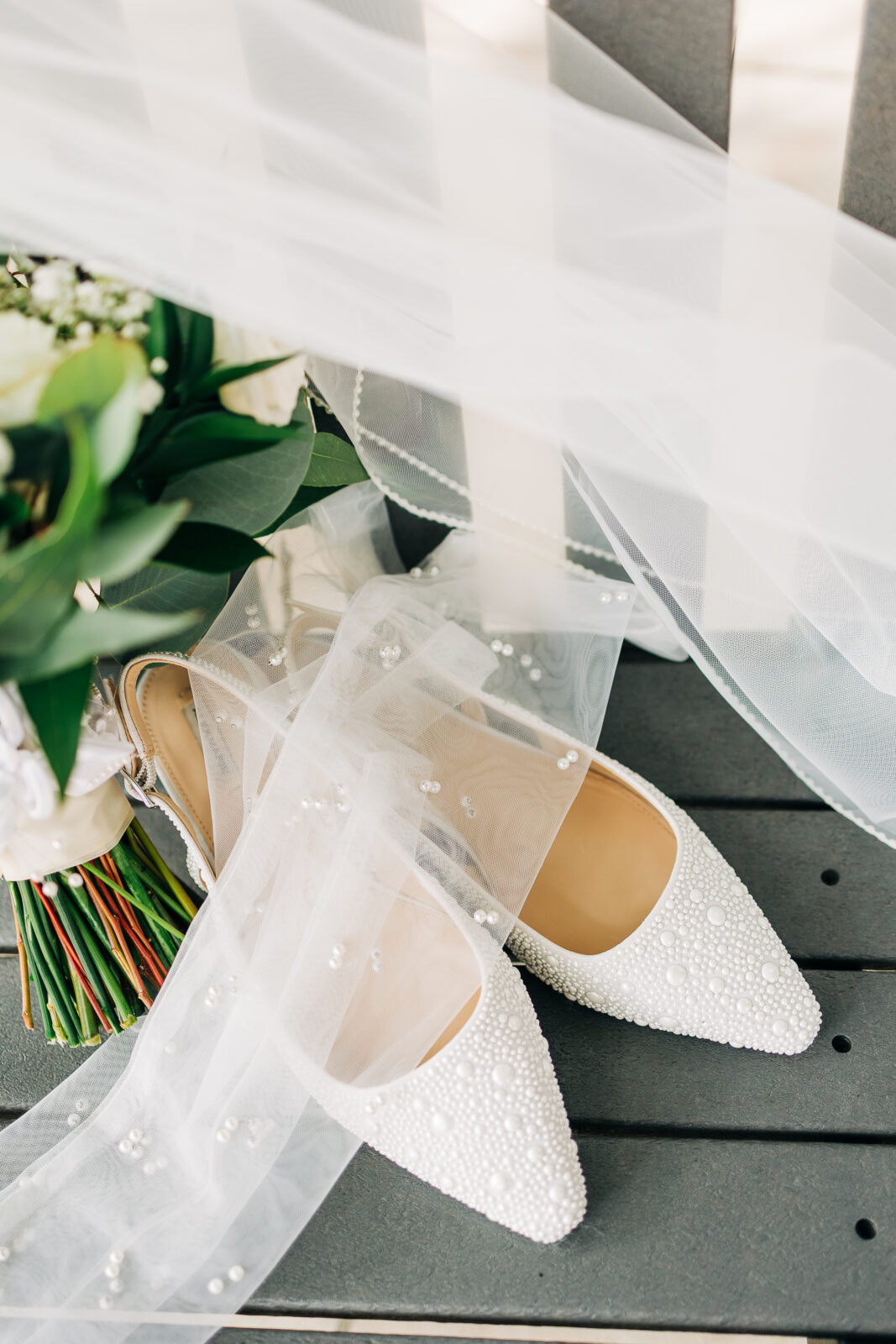 Bride's pearled pointed-toe wedding shoes next to bouquet and veil at Oakbrook Farms