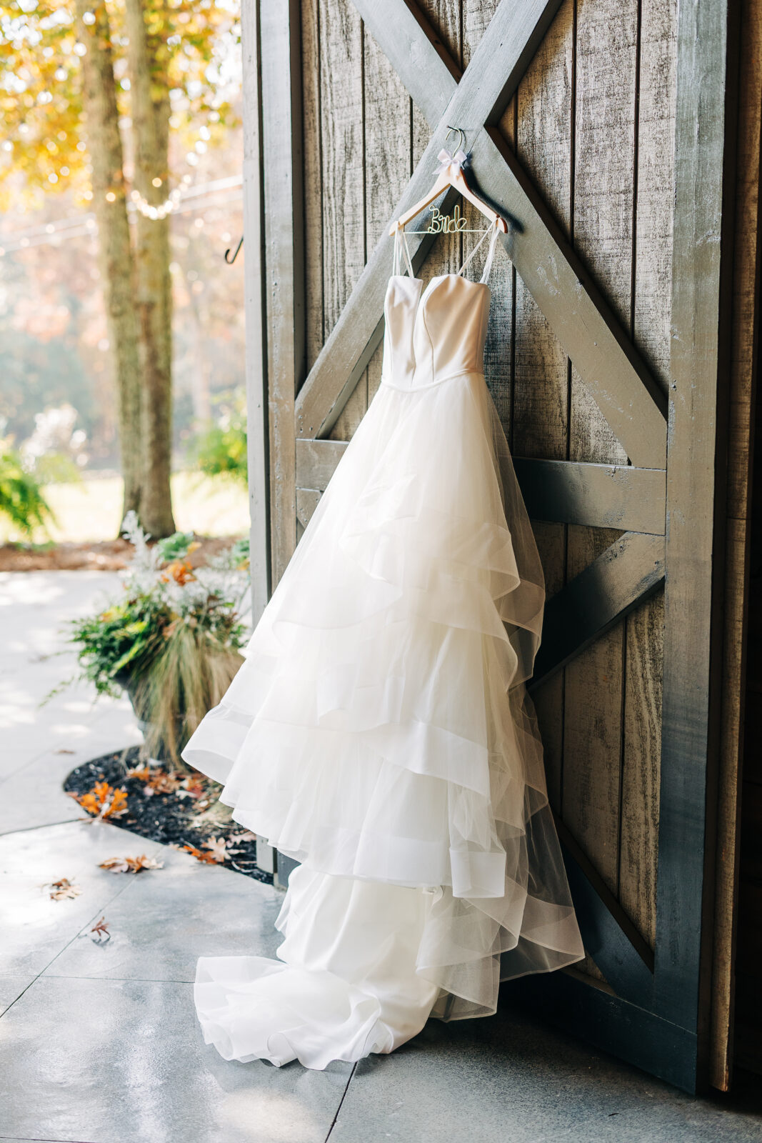 Bride's tiered wedding dress hanging on rustic barn door at Oakbrook Farms Southern Wedding