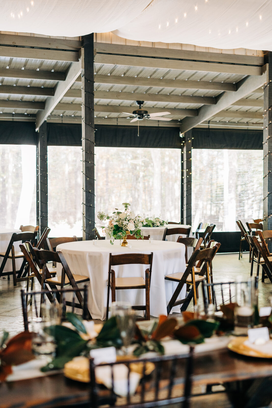 Indoor-outdoor reception tables and cross-back chairs at the Oakbrook Farms wedding venue