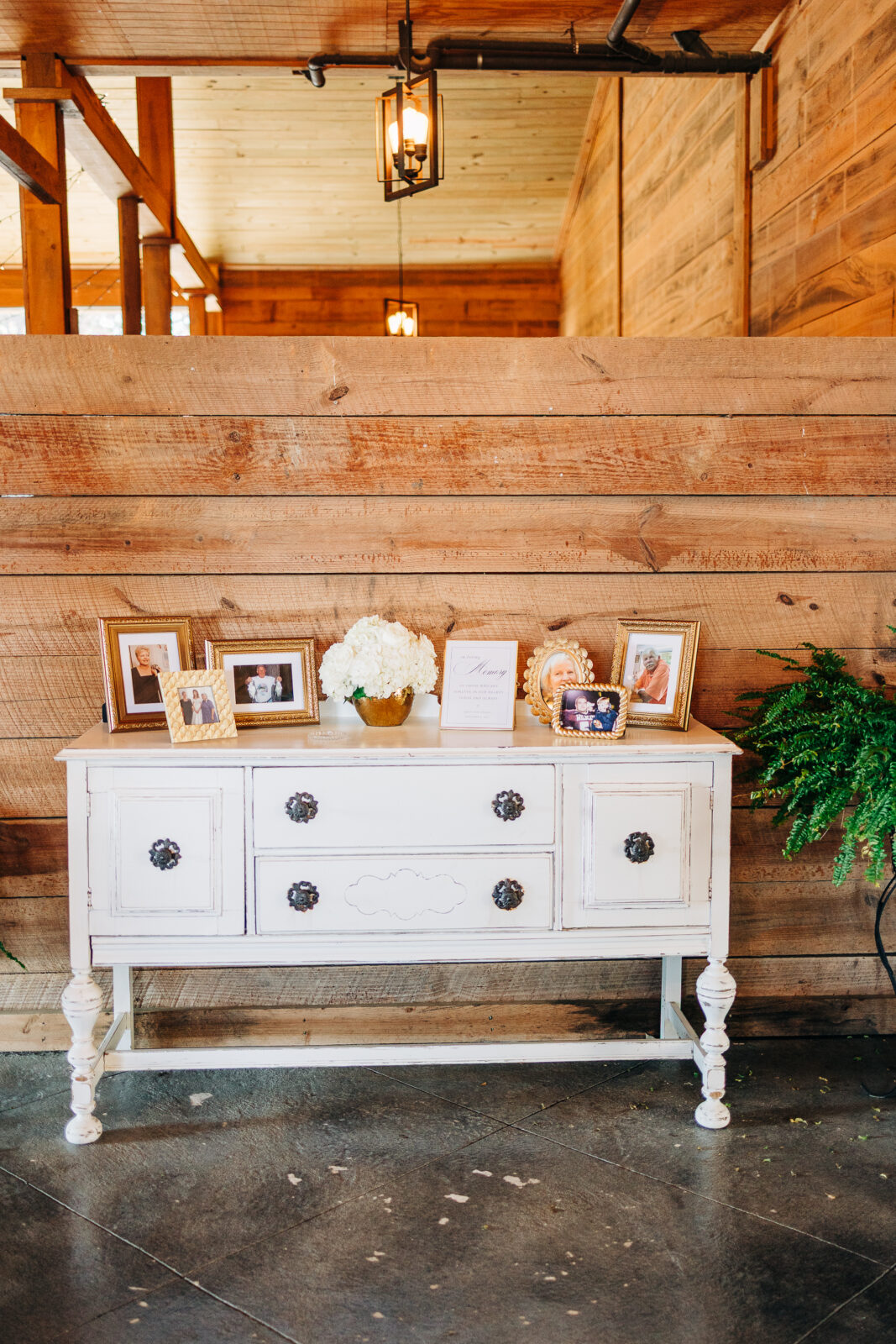 White distressed sideboard decor with framed family photos at Oakbrook Farms Southern Wedding
