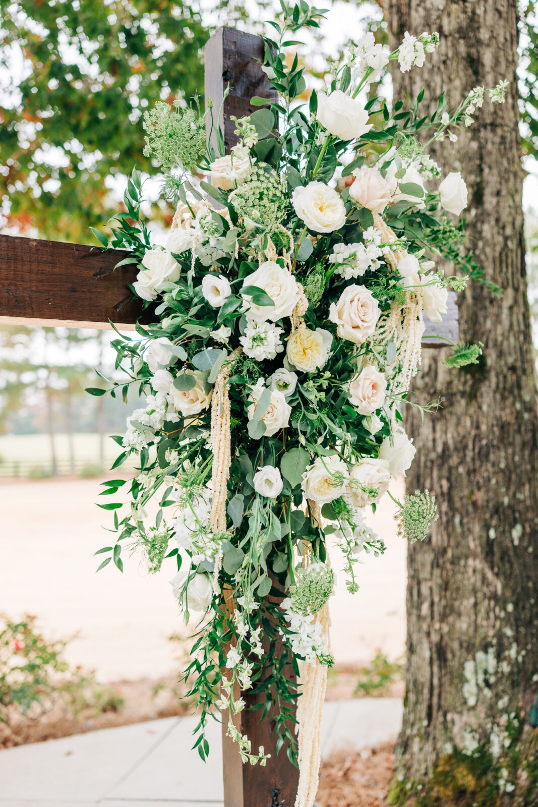White and pale pink floral arrangement on the wooden ceremony cross at Oakbrook Farms