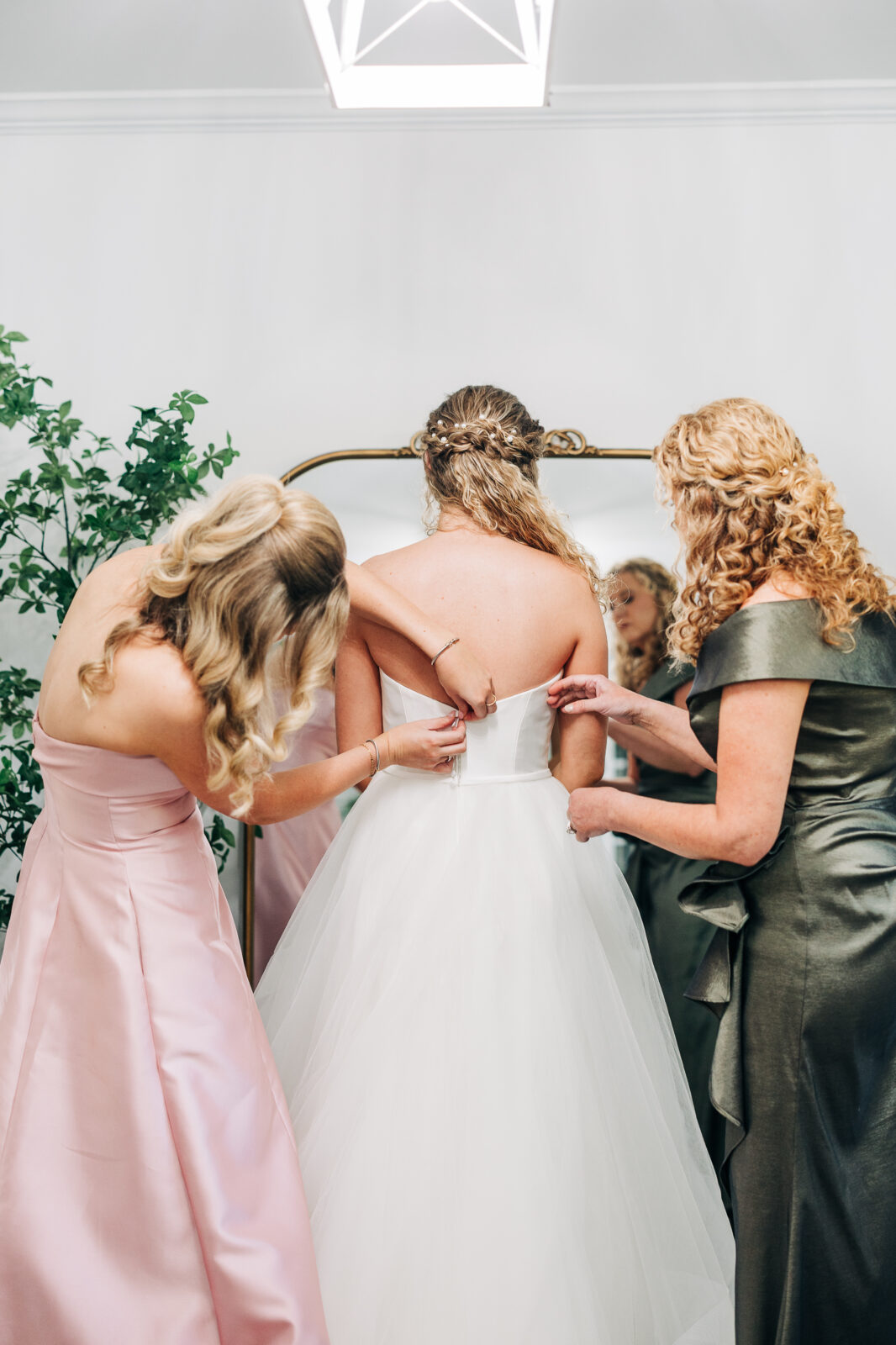 Mother and bridesmaid zipping up the back of bride's wedding dress at Oakbrook Farms South Carolina