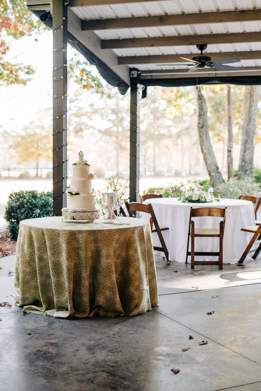 Three-tiered white wedding cake display outside the Oakbrook Farms reception area