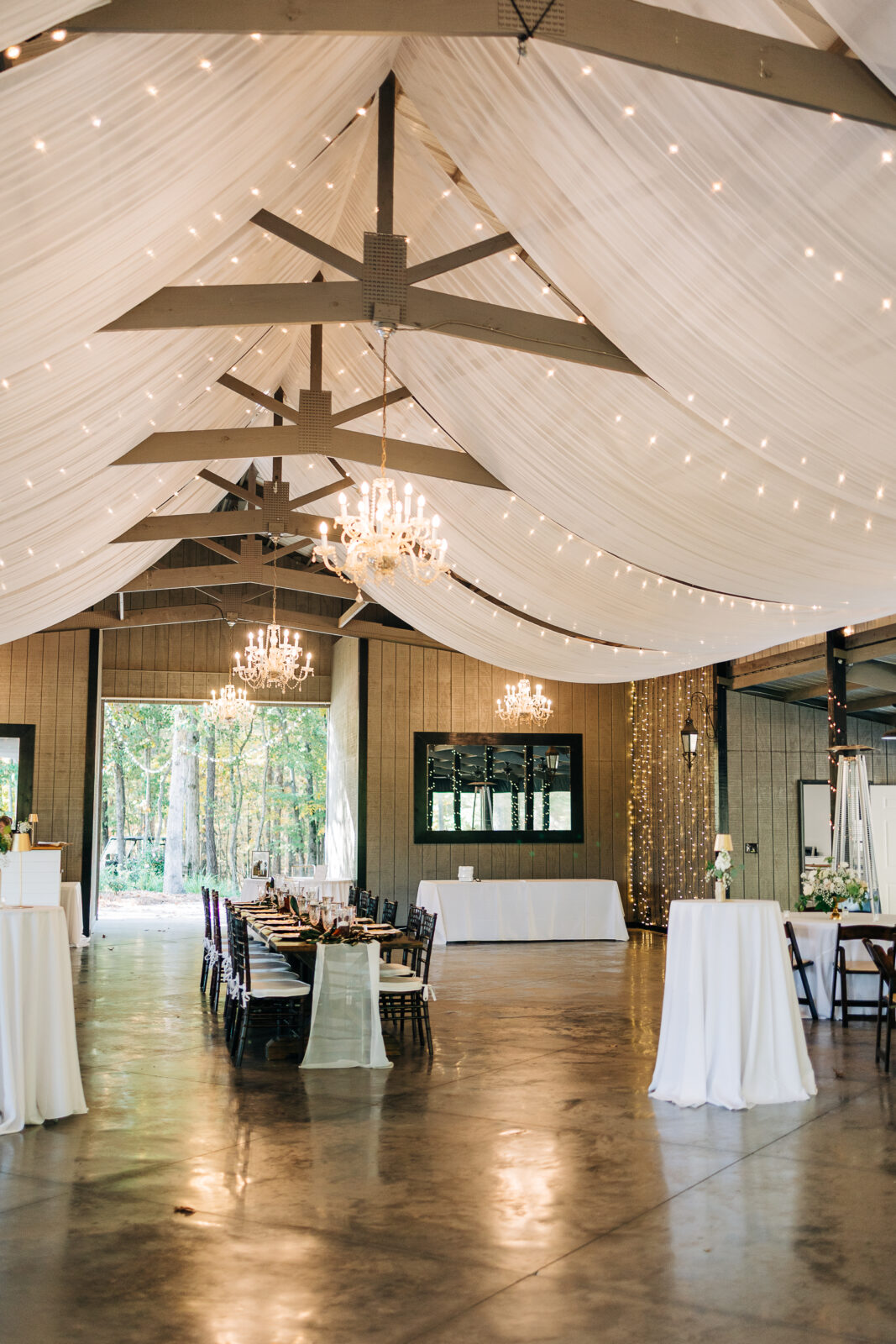 Draped reception barn interior with chandeliers and long tables at Oakbrook Farms Southern Wedding