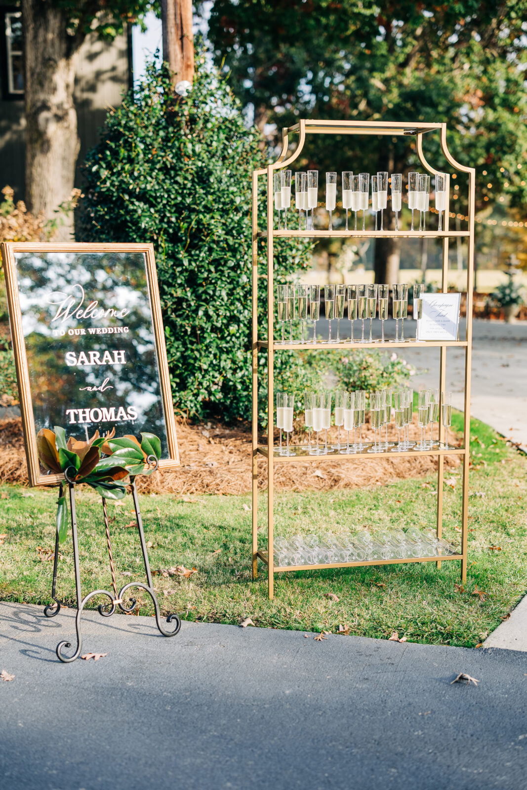 Outdoor gold champagne flute display and mirrored welcome sign at Oakbrook Farms Wedding South Carolina