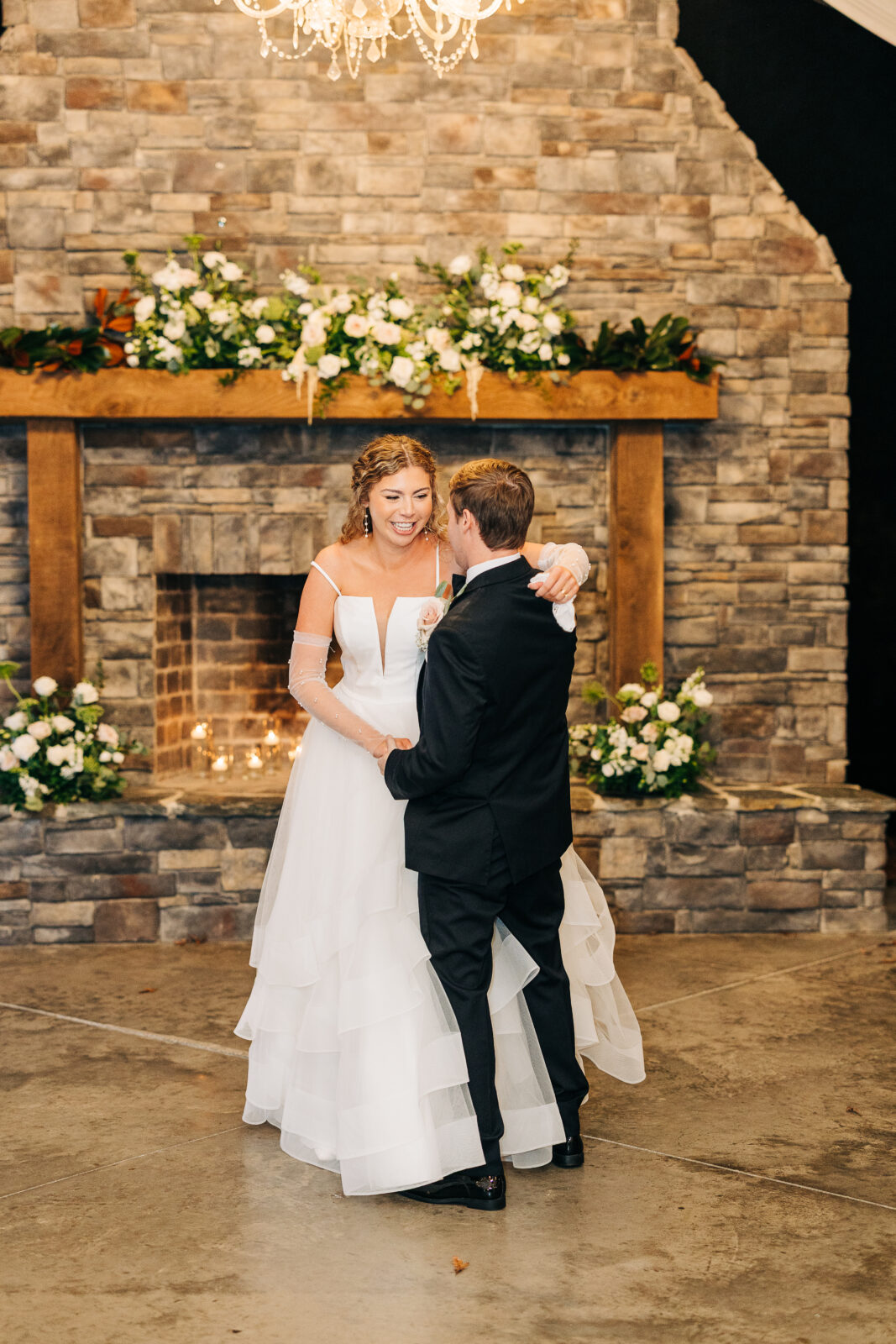 Bride and groom first dance in front of the rustic stone fireplace at Oakbrook Farms reception