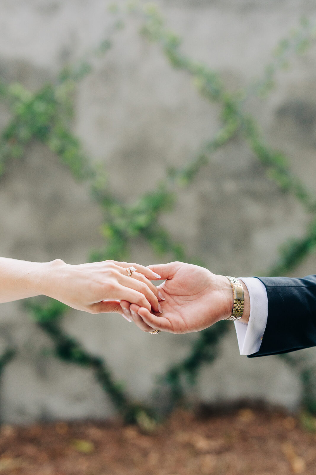 Showing the bride's marquise diamond engagement ring and the groom's gold wedding band