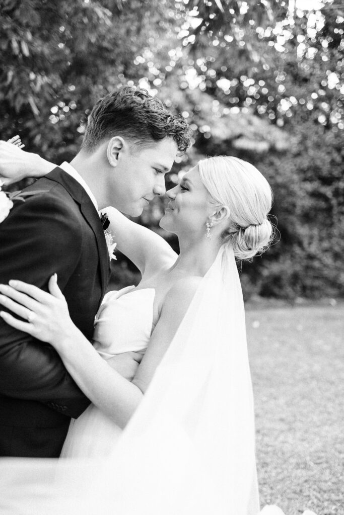 Black and white, slightly grainy close-up of the bride and groom embracing and smiling at each other