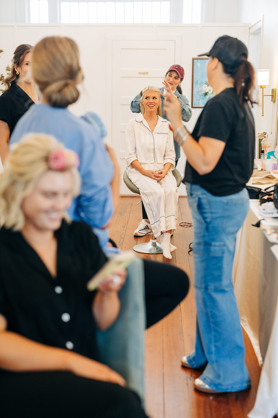 The bride getting her hair styled by an attendant while sitting in pajamas before her Hartley House Wedding South Carolina