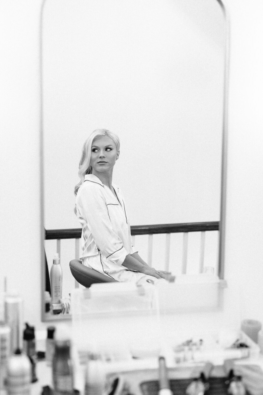 Black and white candid shot of the bride, dressed in silk pajamas, sitting in front of a mirror while getting ready for the Hartley House Wedding South Carolina