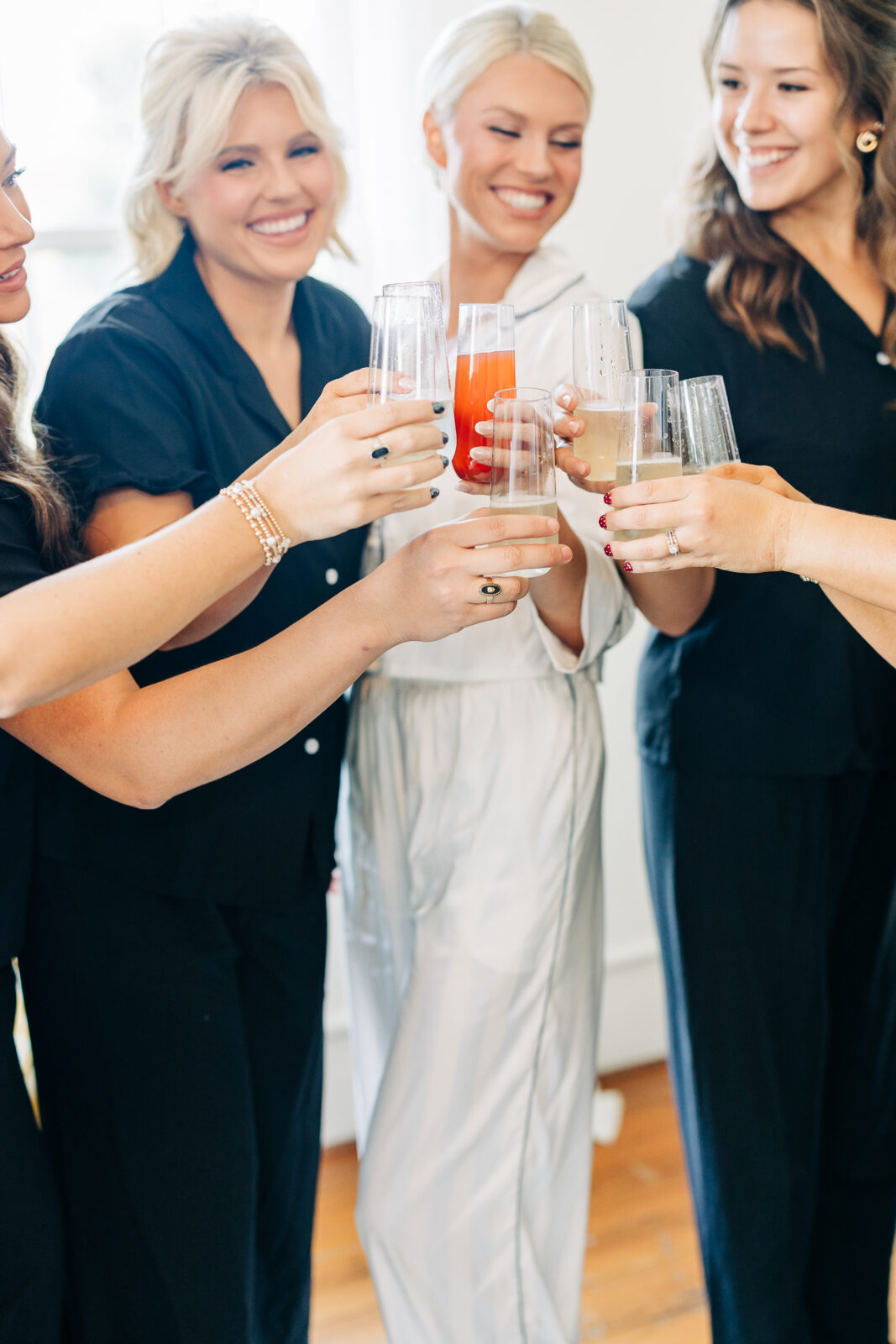 Close-up of the bride and bridesmaids in pajamas toasting with champagne flutes before their Hartley House Wedding South Carolina