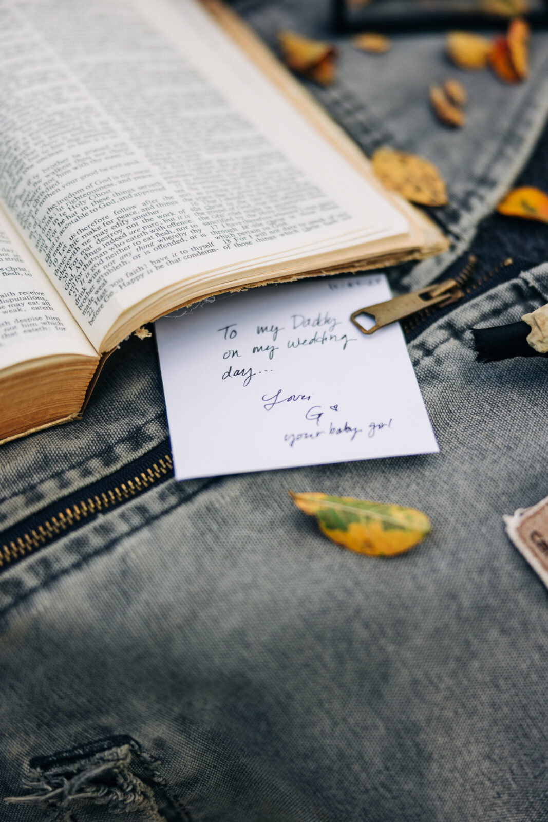 A bridesmaid in black pajamas carefully zips up the bride's white, strapless, tiered wedding gown in the bright getting-ready room
