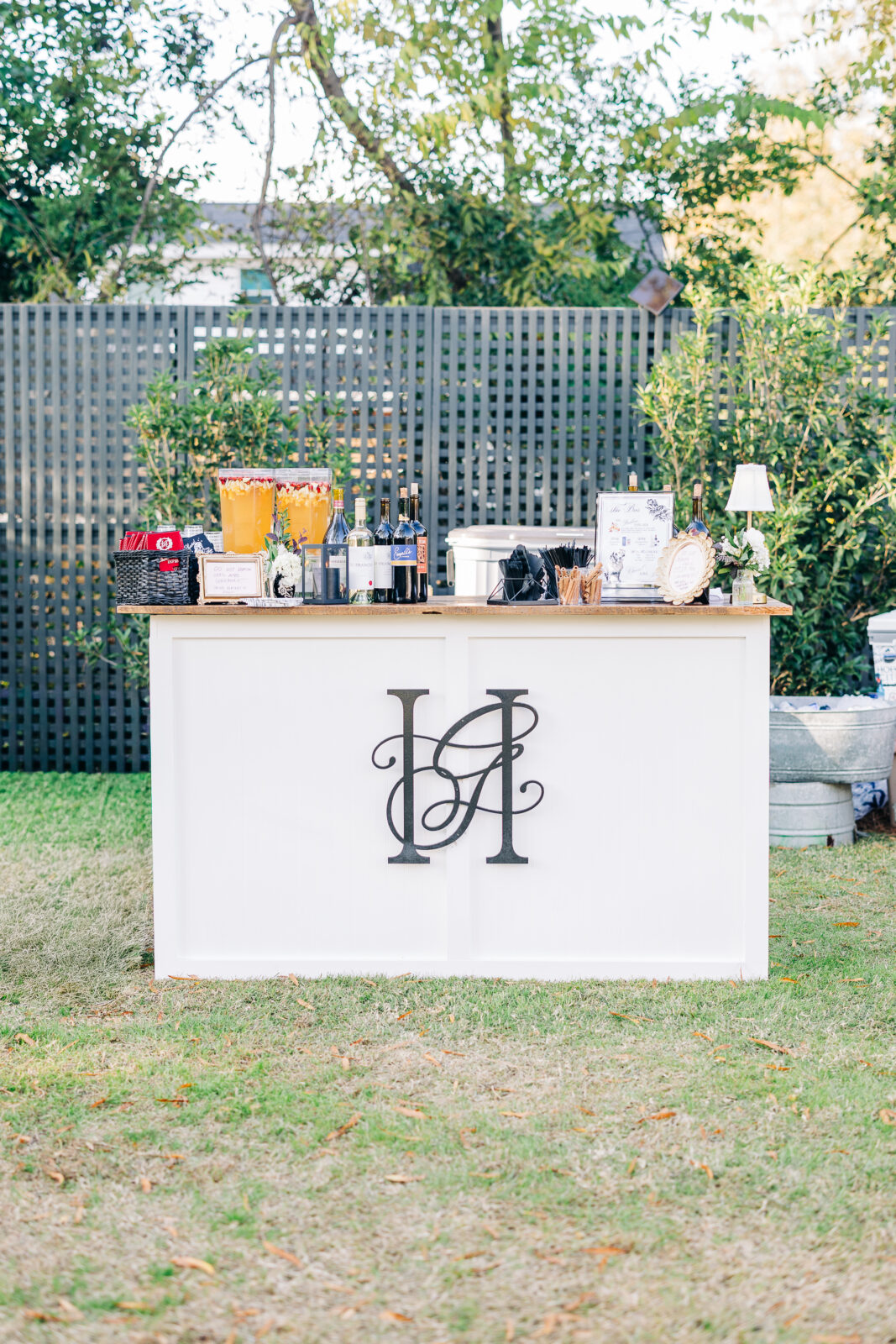 Outdoor view of the white reception bar with the couple's black monogram