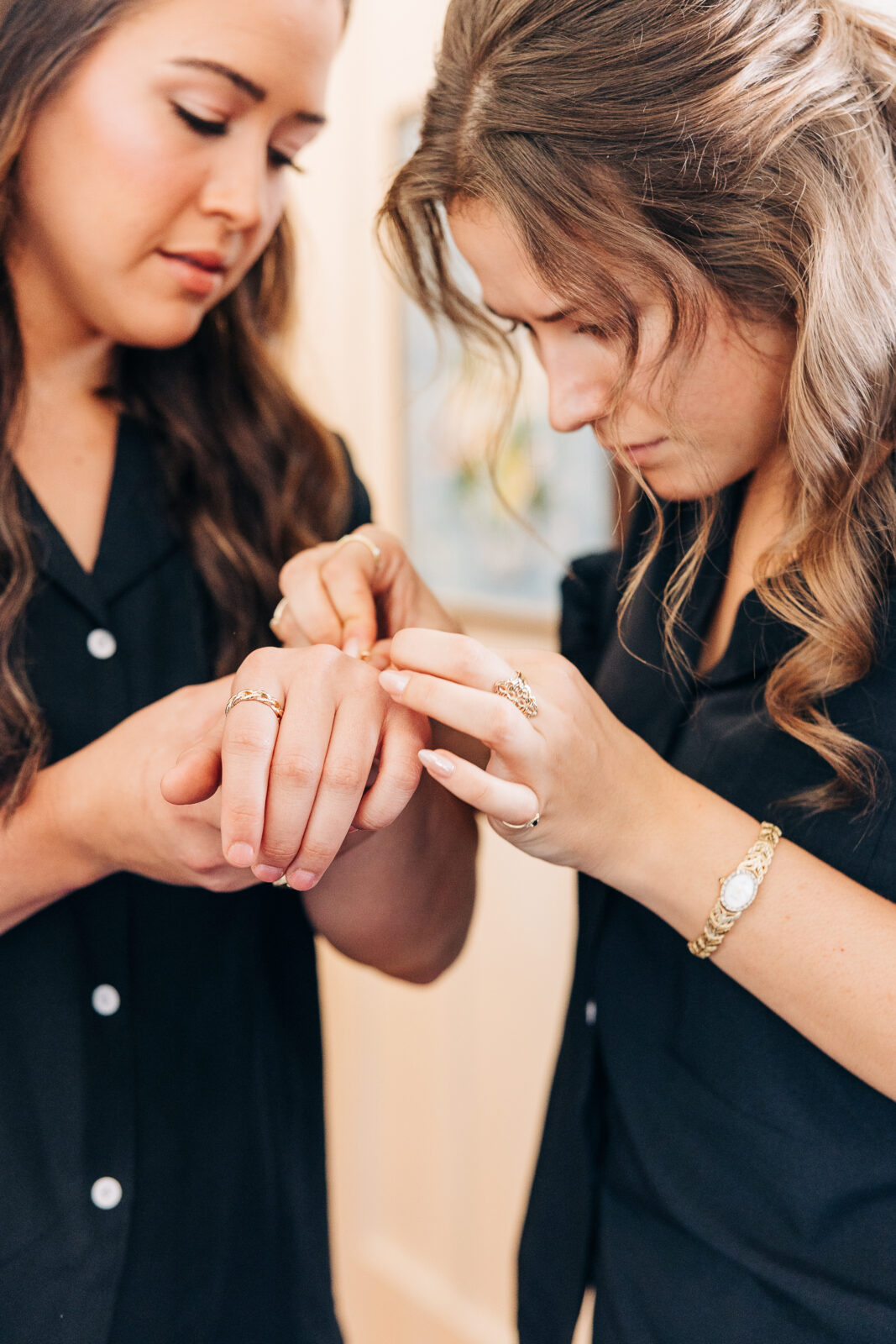 Two bridesmaids in black pajamas helping each other with rings and jewelry before the Hartley House Wedding South Carolina
