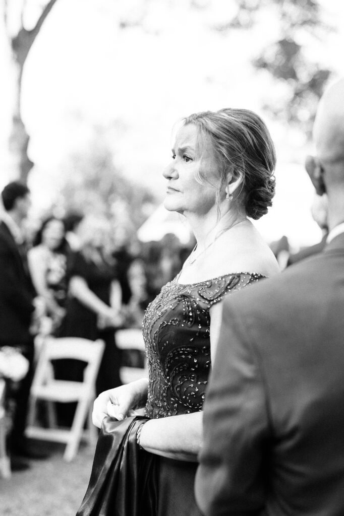 Black and white photo of an elegantly dressed older woman, possibly the mother of the bride or groom, looking on during the outdoor ceremony at the Hartley House Wedding South Carolina