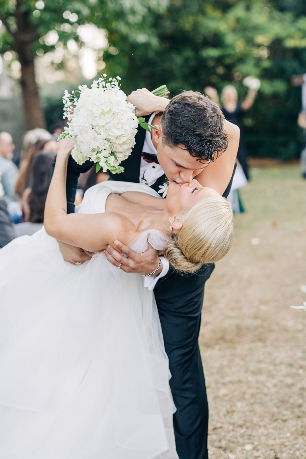 A joyful moment immediately following the vows, as the groom dips and kisses the bride while she holds her white bouquet high during the Hartley House Wedding South Carolina ceremony