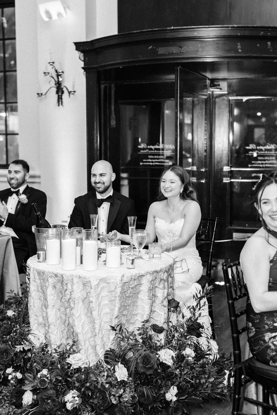 Bride and groom smiling during the reception at 1208 Washington Place with candles and florals decorating their sweetheart table.